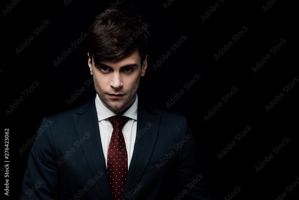 serious businessman in suit looking at camera isolated on black serious businessman in suit looking at camera isolated on black