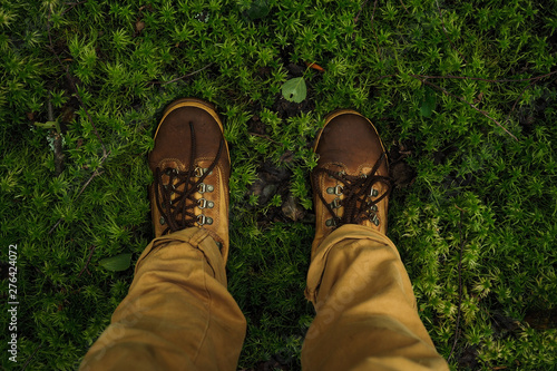 POV legs standing on beautiful green moss in brown pants and wet hikers © Антон Попов