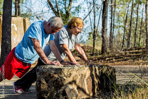 Marriage of elderly doing pushups on outdoor workout