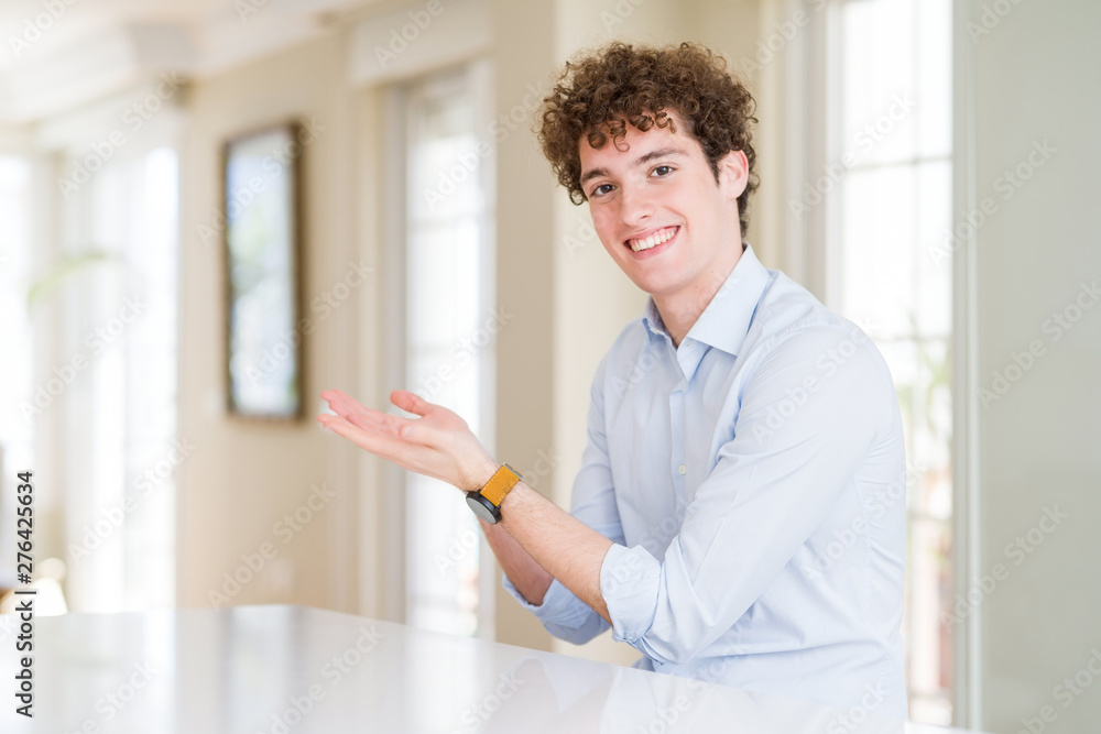 Young business man with curly read head pointing aside with hands open palms showing copy space, presenting advertisement smiling excited happy Young business man with curly read head pointing aside with hands open palms showing copy space, presenting advertisement smiling excited happy