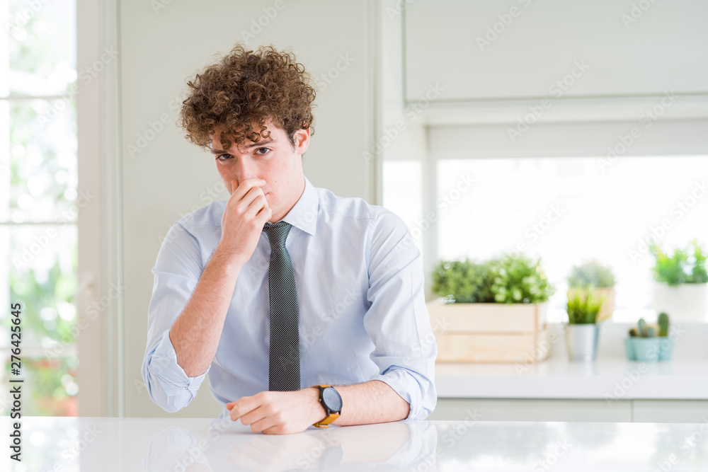 Young business man wearing a tie smelling something stinky and disgusting, intolerable smell, holding breath with fingers on nose. Bad smells concept. Young business man wearing a tie smelling something stinky and disgusting, intolerable smell, holding breath with fingers on nose. Bad smells concept.