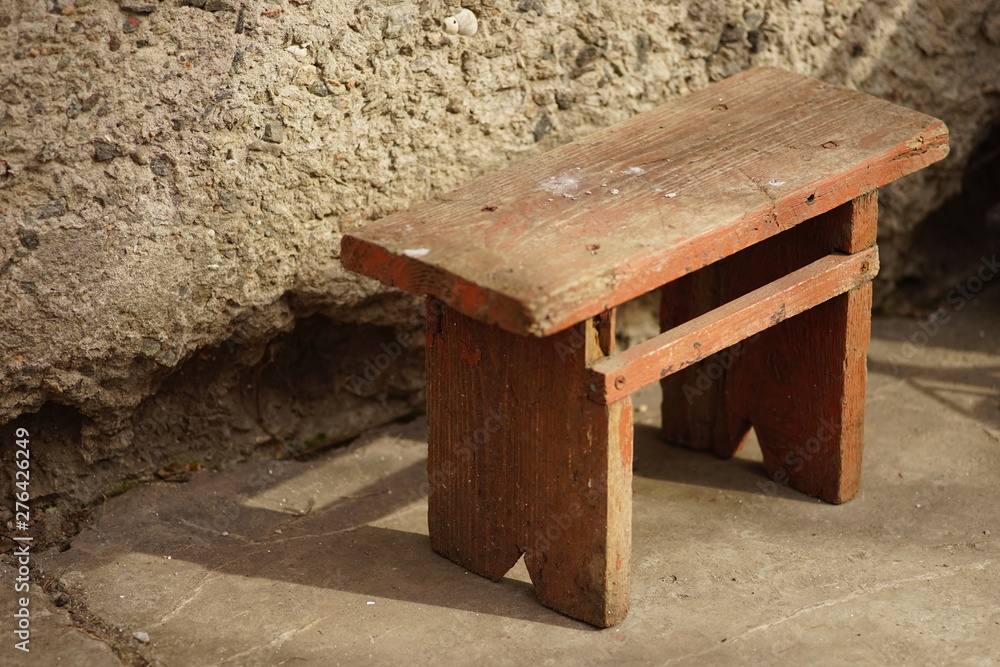 Old brown wooden low stool in the yard with sunlight. Old brown wooden low stool in the yard with sunlight.