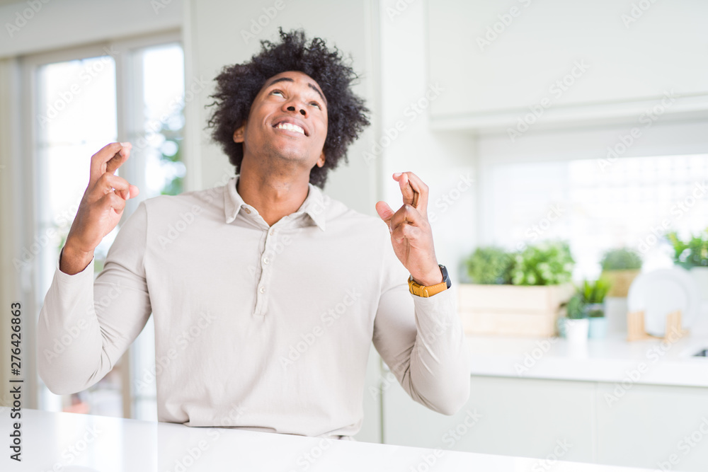 African American man at home smiling crossing fingers with hope and eyes closed. Luck and superstitious concept. African American man at home smiling crossing fingers with hope and eyes closed. Luck and superstitious concept.