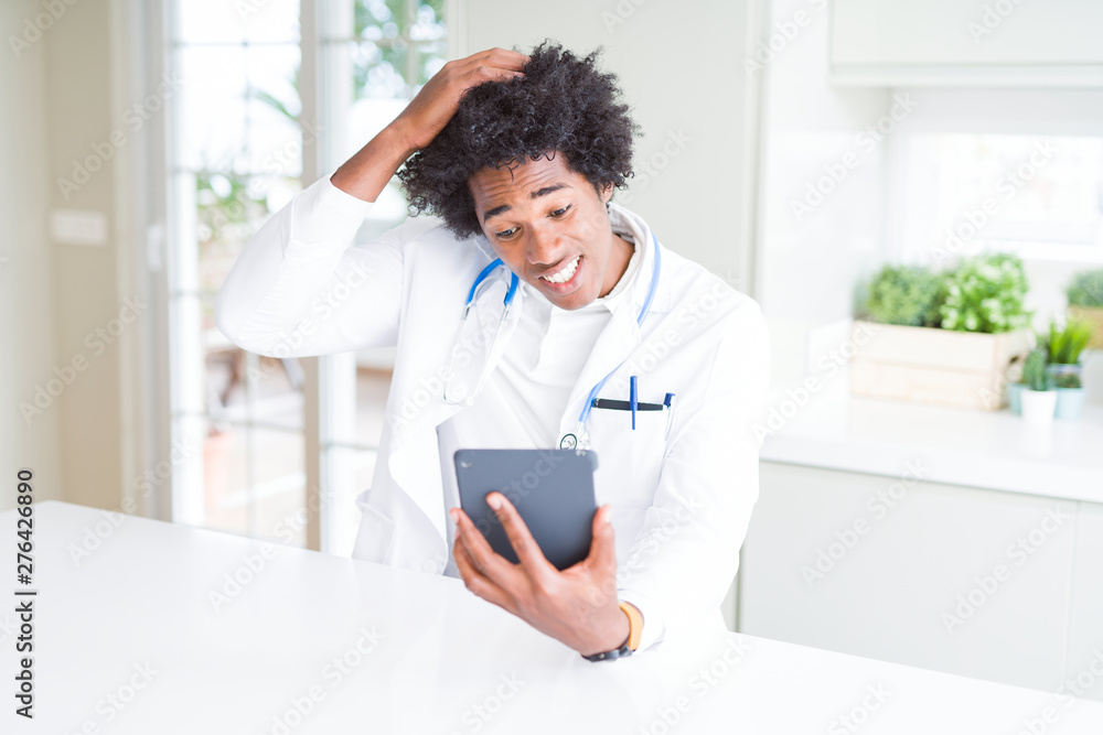African American doctor man using tablet at the clinic stressed with hand on head, shocked with shame and surprise face, angry and frustrated. Fear and upset for mistake. African American doctor man using tablet at the clinic stressed with hand on head, shocked with shame and surprise face, angry and frustrated. Fear and upset for mistake.
