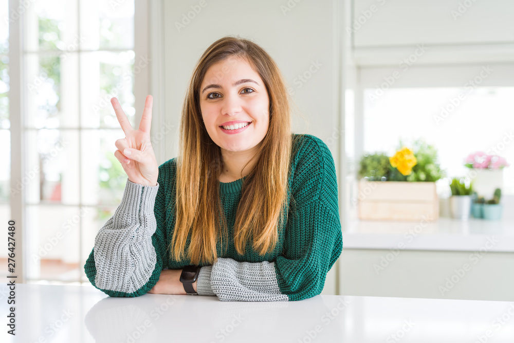 Young beautiful plus size woman wearing casual striped sweater showing and pointing up with fingers number two while smiling confident and happy. Young beautiful plus size woman wearing casual striped sweater showing and pointing up with fingers number two while smiling confident and happy.