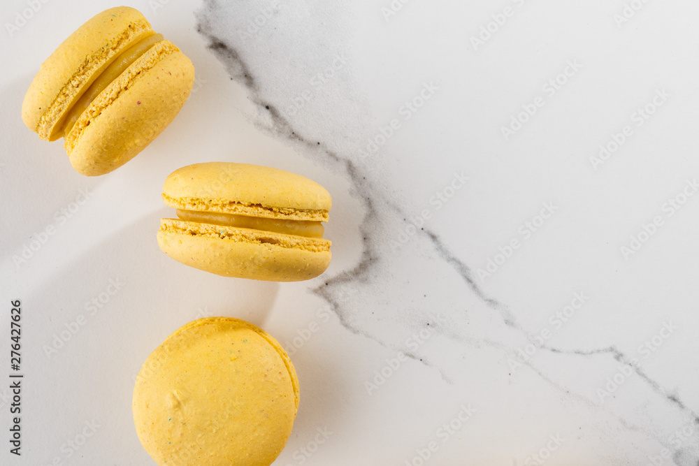 French macaroons isolated. Selective focus. Beautiful yellow macaroons on marble background. Stylish arrangement sweet. Flat lay, top view. Macro photo. With copy space. French macaroons isolated. Selective focus. Beautiful yellow macaroons on marble background. Stylish arrangement sweet. Flat lay, top view. Macro photo. With copy space.