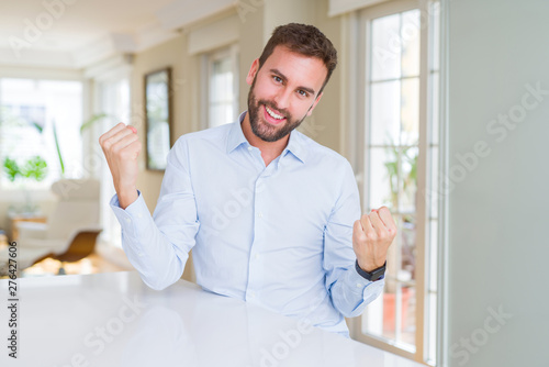 Handsome business man celebrating surprised and amazed for success with arms raised and open eyes. Winner concept. © Krakenimages.com