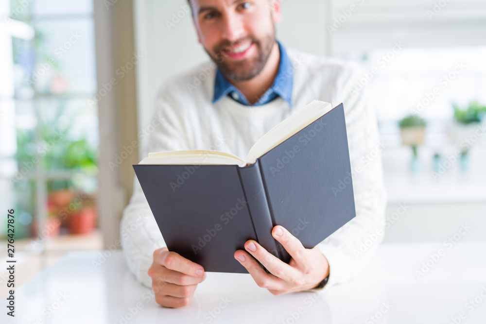 Handsome man reading a book at home