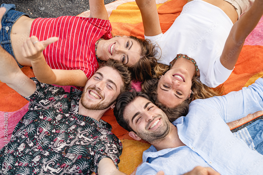 a group of friends lying on a towel having fun together. Millennials lifestyle leisure concept.