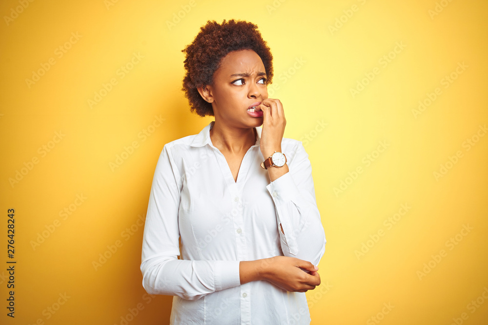 African american business woman over isolated yellow background looking stressed and nervous with hands on mouth biting nails. Anxiety problem. African american business woman over isolated yellow background looking stressed and nervous with hands on mouth biting nails. Anxiety problem.