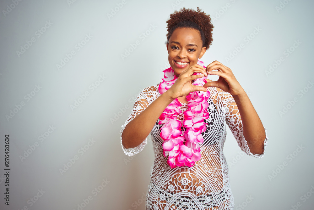 Young african american woman with afro hair wearing flower hawaiian lei over isolated background smiling in love showing heart symbol and shape with hands. Romantic concept. Young african american woman with afro hair wearing flower hawaiian lei over isolated background smiling in love showing heart symbol and shape with hands. Romantic concept.