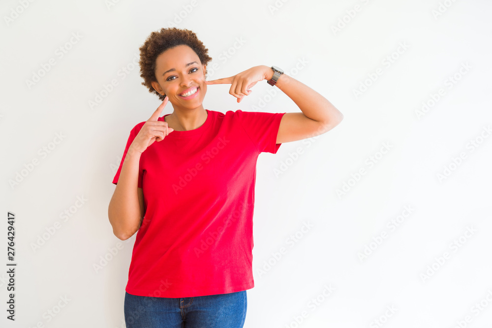 Young beautiful african american woman over white background smiling confident showing and pointing with fingers teeth and mouth. Health concept. Young beautiful african american woman over white background smiling confident showing and pointing with fingers teeth and mouth. Health concept.