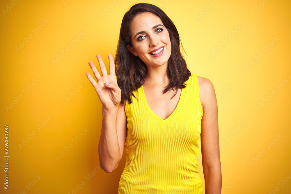 Young beautiful woman wearing t-shirt standing over yellow isolated background showing and pointing up with fingers number four while smiling confident and happy. Young beautiful woman wearing t-shirt standing over yellow isolated background showing and pointing up with fingers number four while smiling confident and happy.