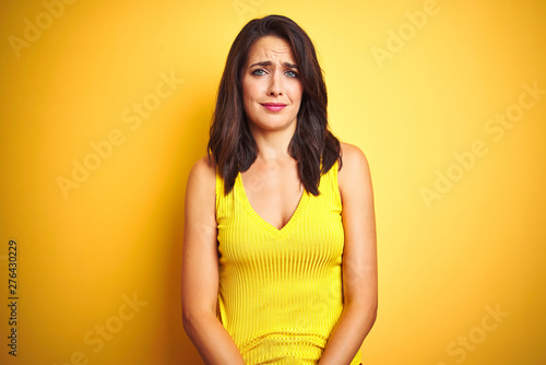 Young beautiful woman wearing t-shirt standing over yellow isolated background depressed and worry for distress, crying angry and afraid. Sad expression.