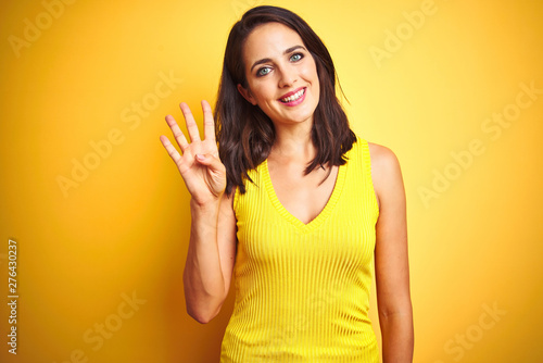 Young beautiful woman wearing t-shirt standing over yellow isolated background showing and pointing up with fingers number four while smiling confident and happy.