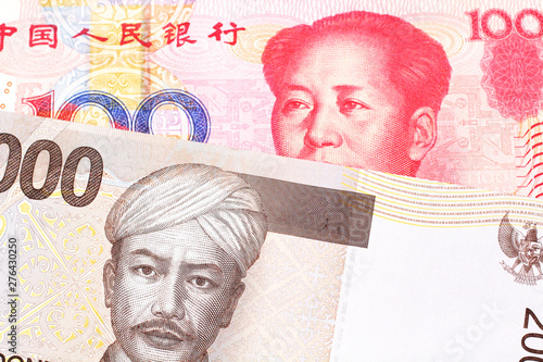 A gray two thousand Indonesian rupiah bank note with a red, one hundred Chinese yuan  photo