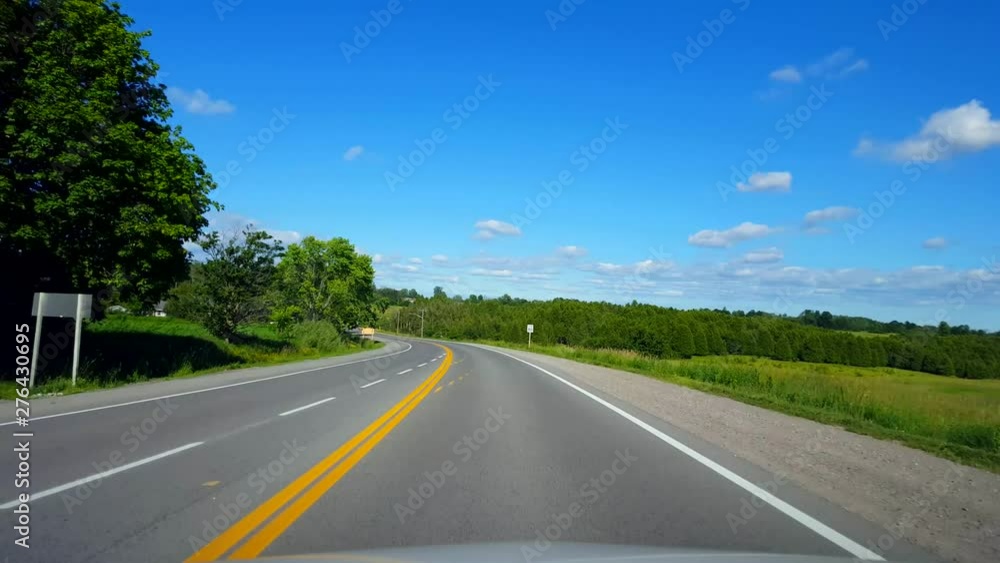 Driving Rural Road Along Forest During Bright Summer Day. Driver Point of View POV Beautiful Lush Green Foliage Lining Countryside Street. Driving Rural Road Along Forest During Bright Summer Day. Driver Point of View POV Beautiful Lush Green Foliage Lining Countryside Street.