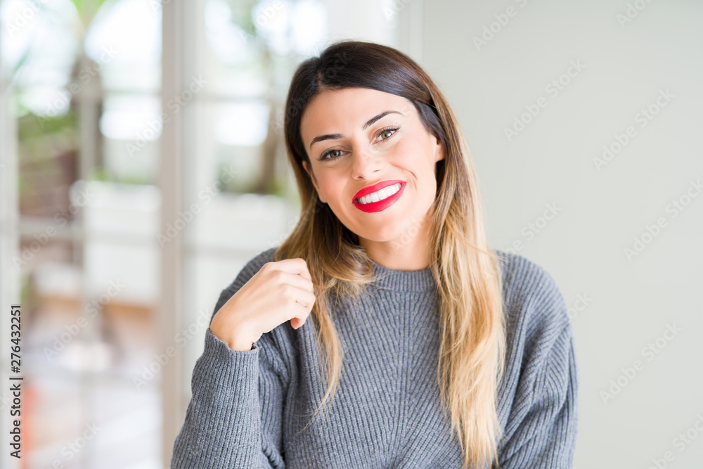 Young beautiful woman wearing winter sweater at home with a happy and cool smile on face. Lucky person.