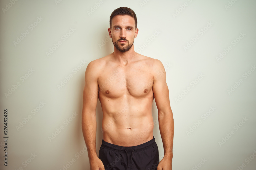 Young handsome shirtless man over isolated background Relaxed with serious expression on face. Simple and natural looking at the camera.