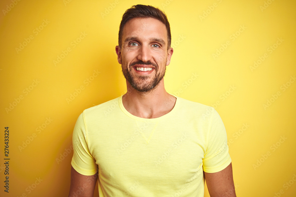 Young handsome man wearing casual yellow t-shirt over yellow isolated background with a happy and cool smile on face. Lucky person. Young handsome man wearing casual yellow t-shirt over yellow isolated background with a happy and cool smile on face. Lucky person.