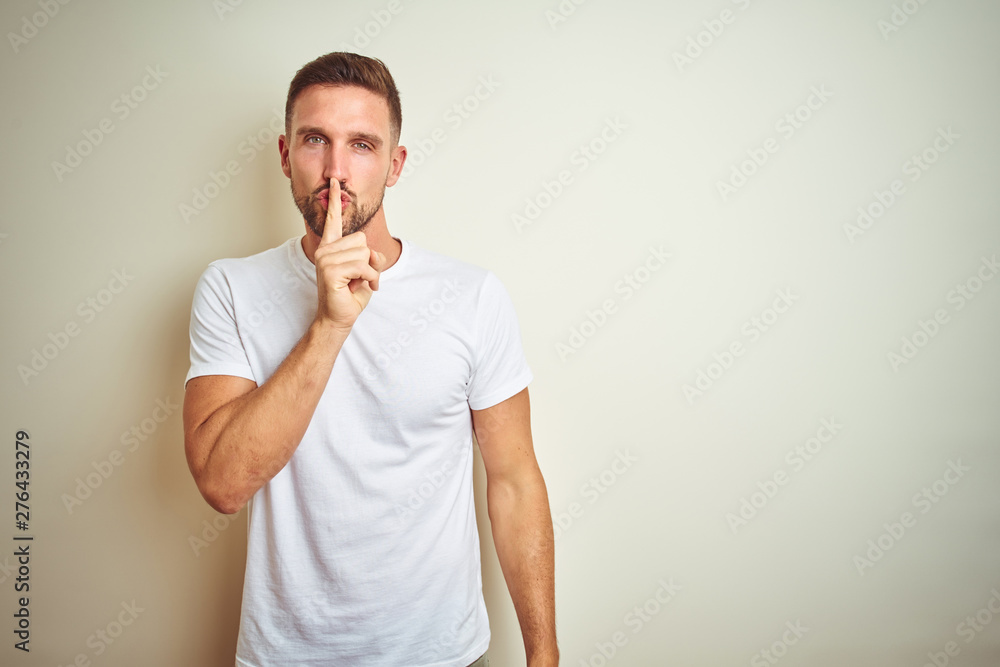 Young handsome man wearing casual white t-shirt over isolated background asking to be quiet with finger on lips. Silence and secret concept. Young handsome man wearing casual white t-shirt over isolated background asking to be quiet with finger on lips. Silence and secret concept.