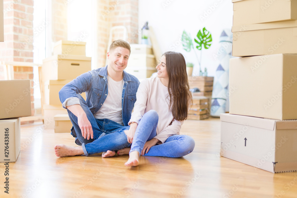 Young beautiful couple relaxing sitting on the floor around cardboard boxes at home, smiling happy moving to a new house Young beautiful couple relaxing sitting on the floor around cardboard boxes at home, smiling happy moving to a new house