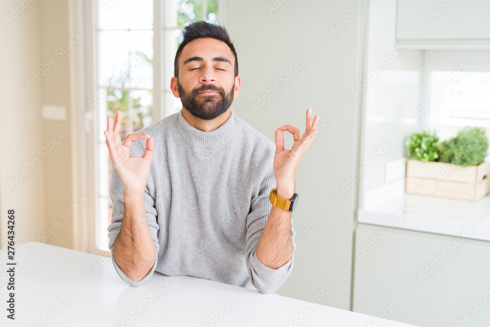 Handsome hispanic man wearing casual sweater at home relax and smiling with eyes closed doing meditation gesture with fingers. Yoga concept. Handsome hispanic man wearing casual sweater at home relax and smiling with eyes closed doing meditation gesture with fingers. Yoga concept.