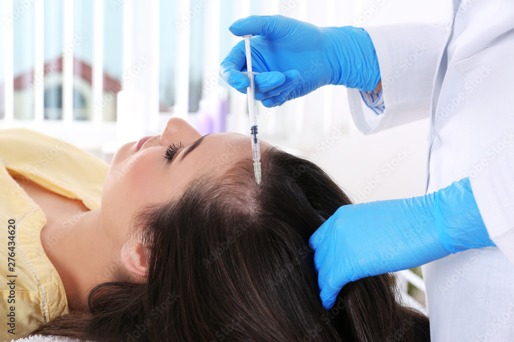 Fototapeta premium Young woman with hair loss problem receiving injection in salon