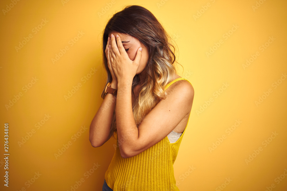 Young beautiful woman wearing t-shirt over yellow isolated background with sad expression covering face with hands while crying. Depression concept. Young beautiful woman wearing t-shirt over yellow isolated background with sad expression covering face with hands while crying. Depression concept.