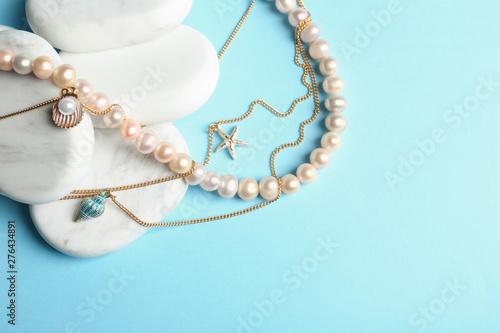 White marble stones with elegant jewelry on light blue background, top view. Space for text