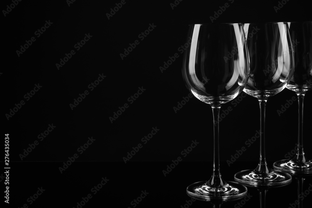 Set of empty wine glasses on black background. Space for text