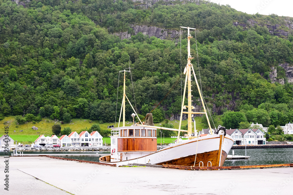 Old wooden fishing boat at the pier. Norwegian village in the mountains by the sea Old wooden fishing boat at the pier. Norwegian village in the mountains by the sea