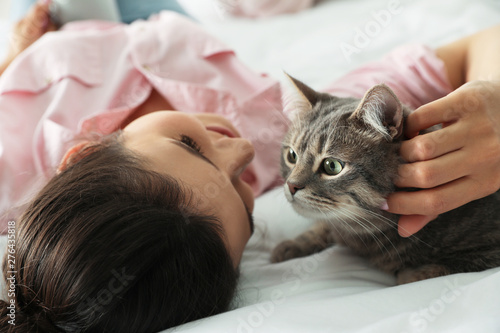 Young woman with cute cat on bed. Pet and owner