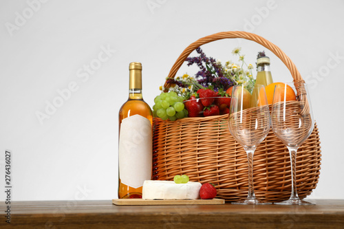 Picnic basket with wine and products on wooden table against white background. Space for text