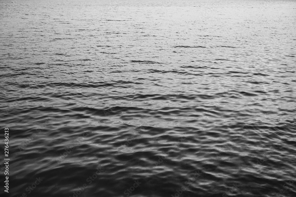 Sea or ocean water with little relaxing waves and reflection in different light. Beautiful gradient with black and white colors. Neutral background and texture. Sea or ocean water with little relaxing waves and reflection in different light. Beautiful gradient with black and white colors. Neutral background and texture.