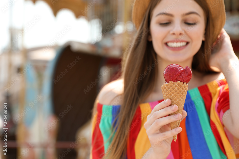 Young happy woman with ice cream cone in amusement park. Space for text