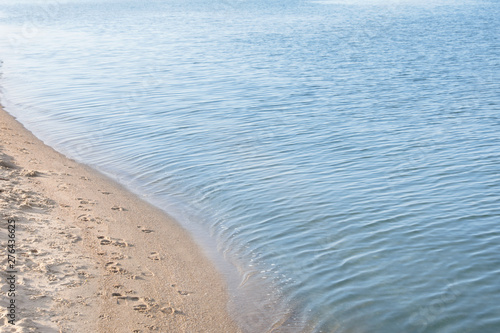 View of sea water and beach sand on sunny summer day