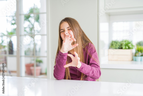 Beautiful young girl kid on white table disgusted expression, displeased and fearful doing disgust face because aversion reaction. With hands raised. Annoying concept.