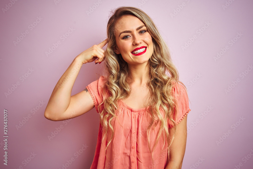 Fototapeta premium Young beautiful woman wearing t-shirt standing over pink isolated background Smiling pointing to head with one finger, great idea or thought, good memory