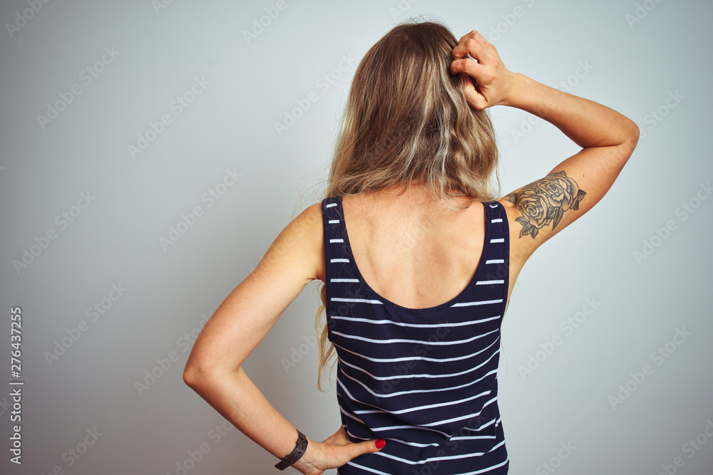 Young beautiful woman wearing stripes t-shirt standing over white isolated background Backwards thinking about doubt with hand on head Young beautiful woman wearing stripes t-shirt standing over white isolated background Backwards thinking about doubt with hand on head