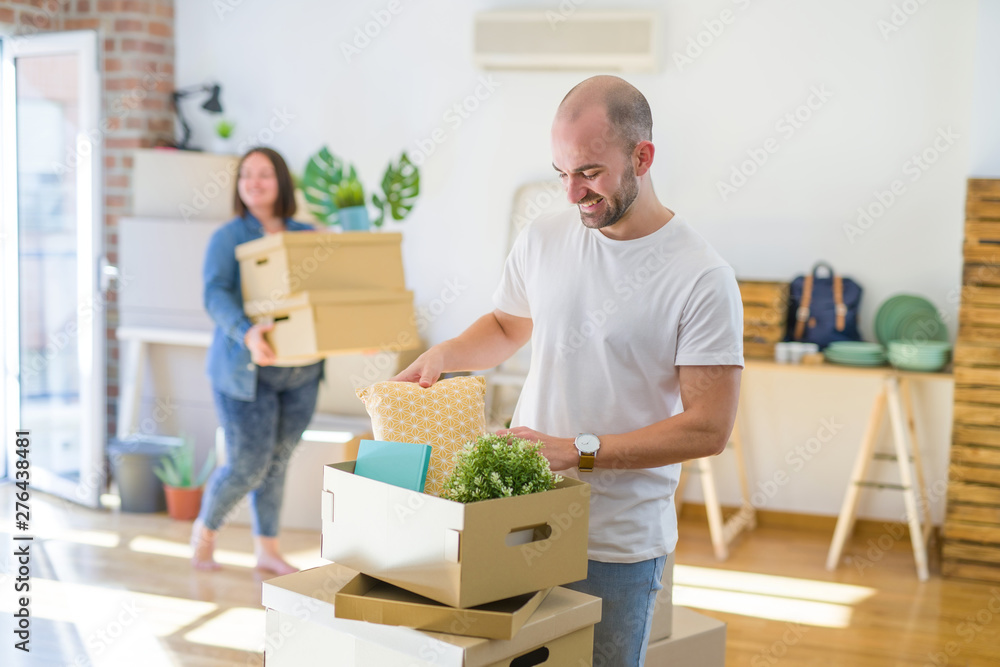 Young couple moving to new apartment, handsome man moving cardboard boxes and smiling happy Young couple moving to new apartment, handsome man moving cardboard boxes and smiling happy