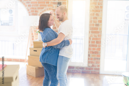 Young couple dancing around cardboard boxes at new home, celebrating smiling very happy new house