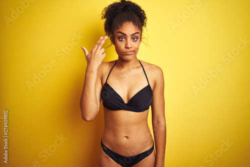 African american woman on vacation wearing bikini standing over isolated yellow background Shooting and killing oneself pointing hand and fingers to head like gun, suicide gesture.