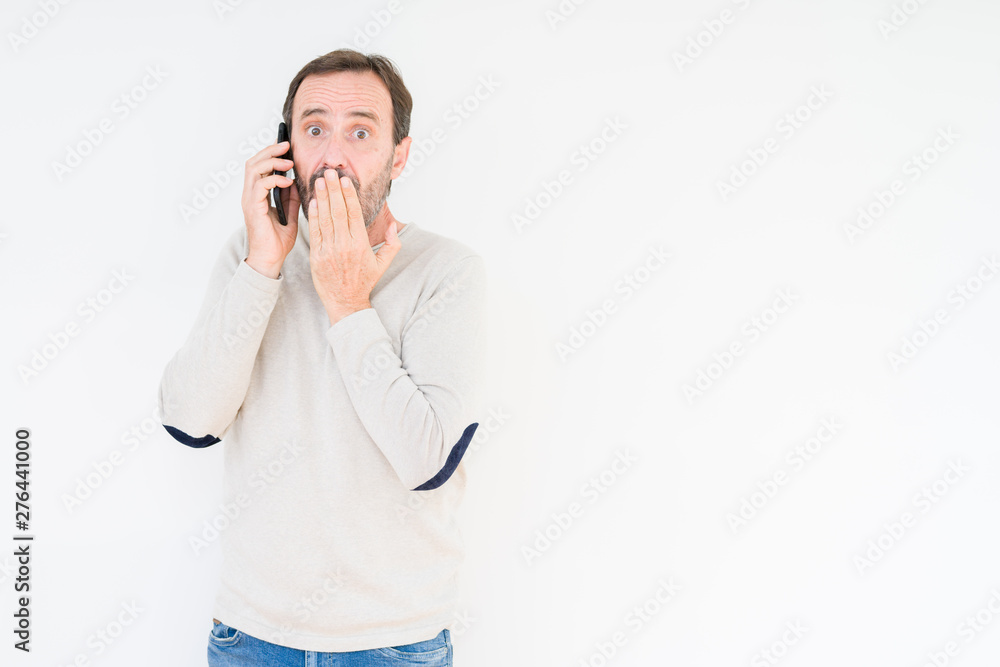 Senior man talking on smartphone over isolated background cover mouth with hand shocked with shame for mistake, expression of fear, scared in silence, secret concept Senior man talking on smartphone over isolated background cover mouth with hand shocked with shame for mistake, expression of fear, scared in silence, secret concept