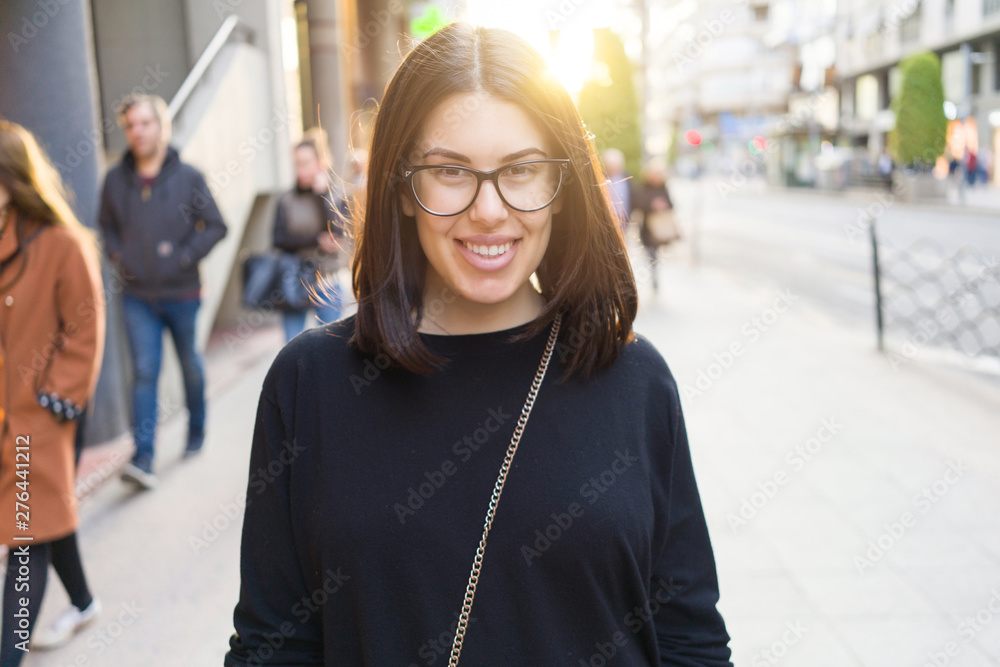 Beautiful young brunette woman smiling excited walking down the city streets, happy and confident expression standing outdoors at the town