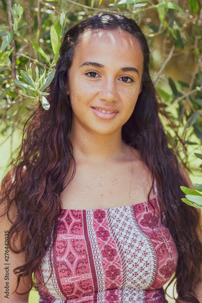 Mixed race young woman stands under an olive tree on a farm Mixed race young woman stands under an olive tree on a farm
