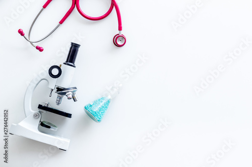 Medical tests on work table of doctor with microscope, stethoscope, test tube, pills on white background top view mockup
