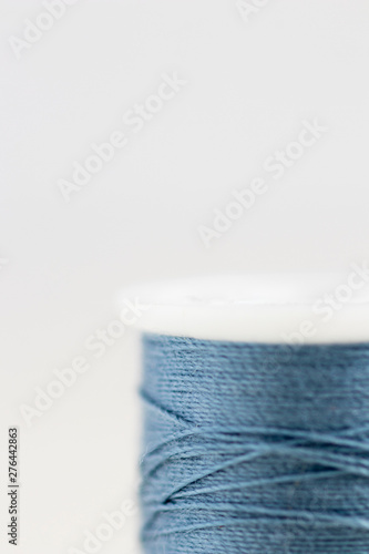 Spool of blue thread with very limited focus on white background. Extreme close-up 