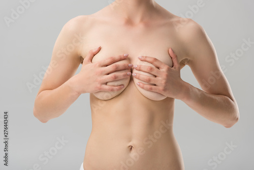 partial view of sexy naked girl covering breast isolated on grey
