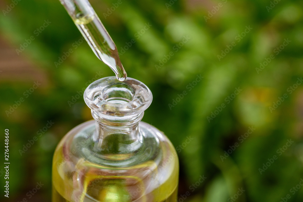 dropper and glass bottle with essential oil on green background dropper and glass bottle with essential oil on green background